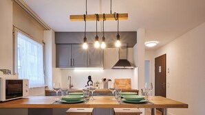 Eine moderne Küche mit einer zentralen Kochinsel, Holzstühlen und Pendelleuchten.