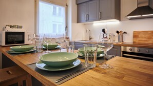 Eine moderne Küche mit Holzarbeitsplatten, grünen Schüsseln, Weingläsern und einer Mikrowelle.