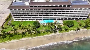 Ein mehrstöckiges Hotel mit Pool und Palmen.