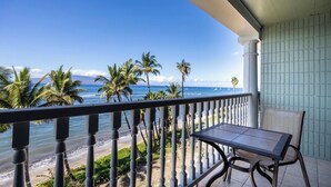 Ein Balkon mit Blick auf Strand und Meer, inklusive Tisch und Stuhl.