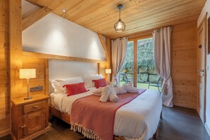 A wooden cabin-style bedroom with a bed, nightstands, and a window with curtains.