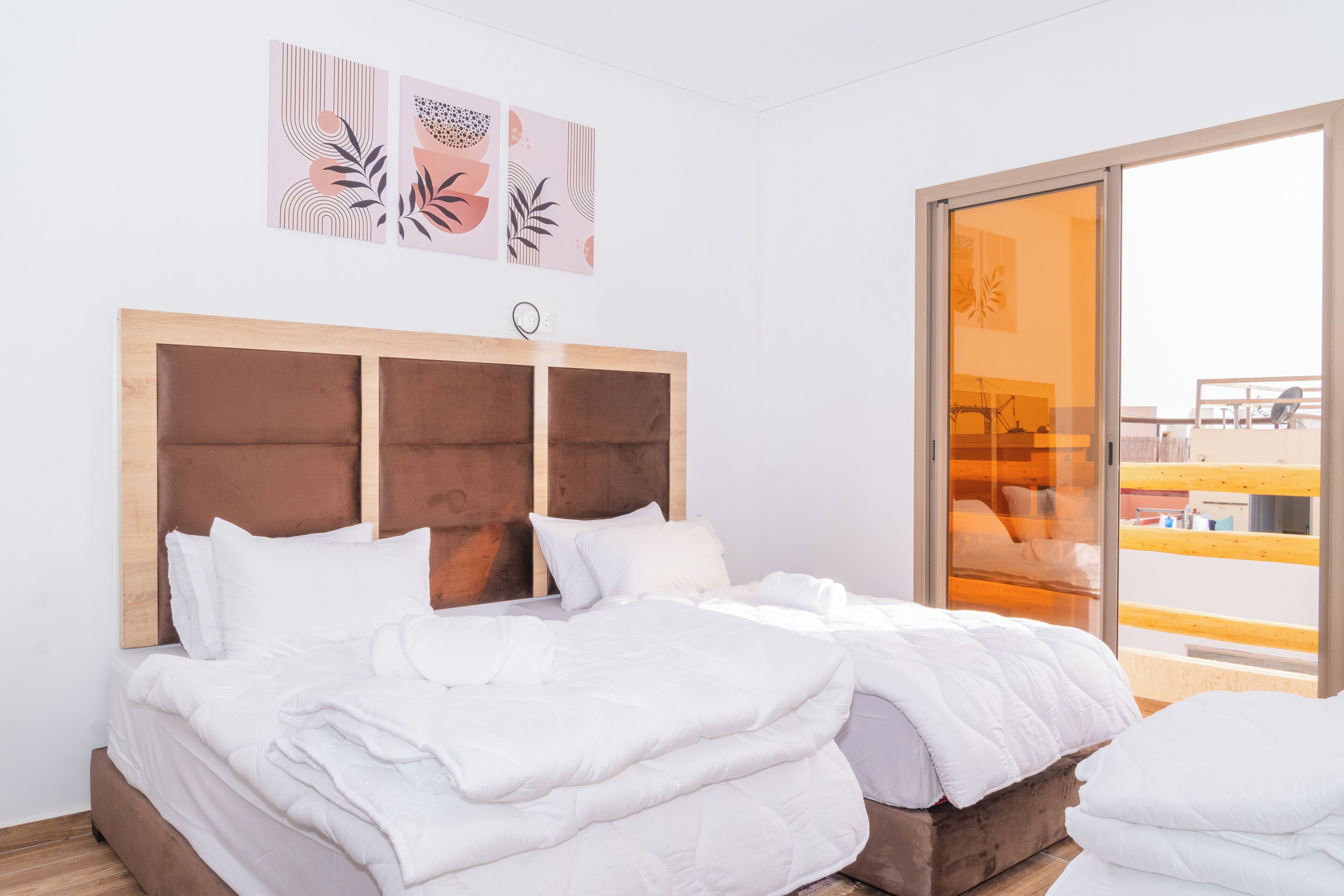A modern hotel room with a large bed, a wooden headboard, and a balcony with a view.
