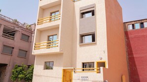 A multi-story building with balconies, a yellow door, and a visible staircase. - TIFAWINE STAY IMSOAUNE SURF AND YOUGA (Imsouane)