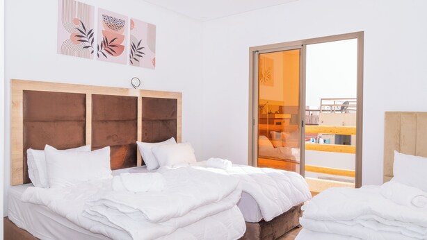 A hotel room with a large bed, a wooden headboard, and a sliding glass door leading to a balcony. - TIFAWINE STAY IMSOAUNE SURF AND YOUGA (Imsouane)