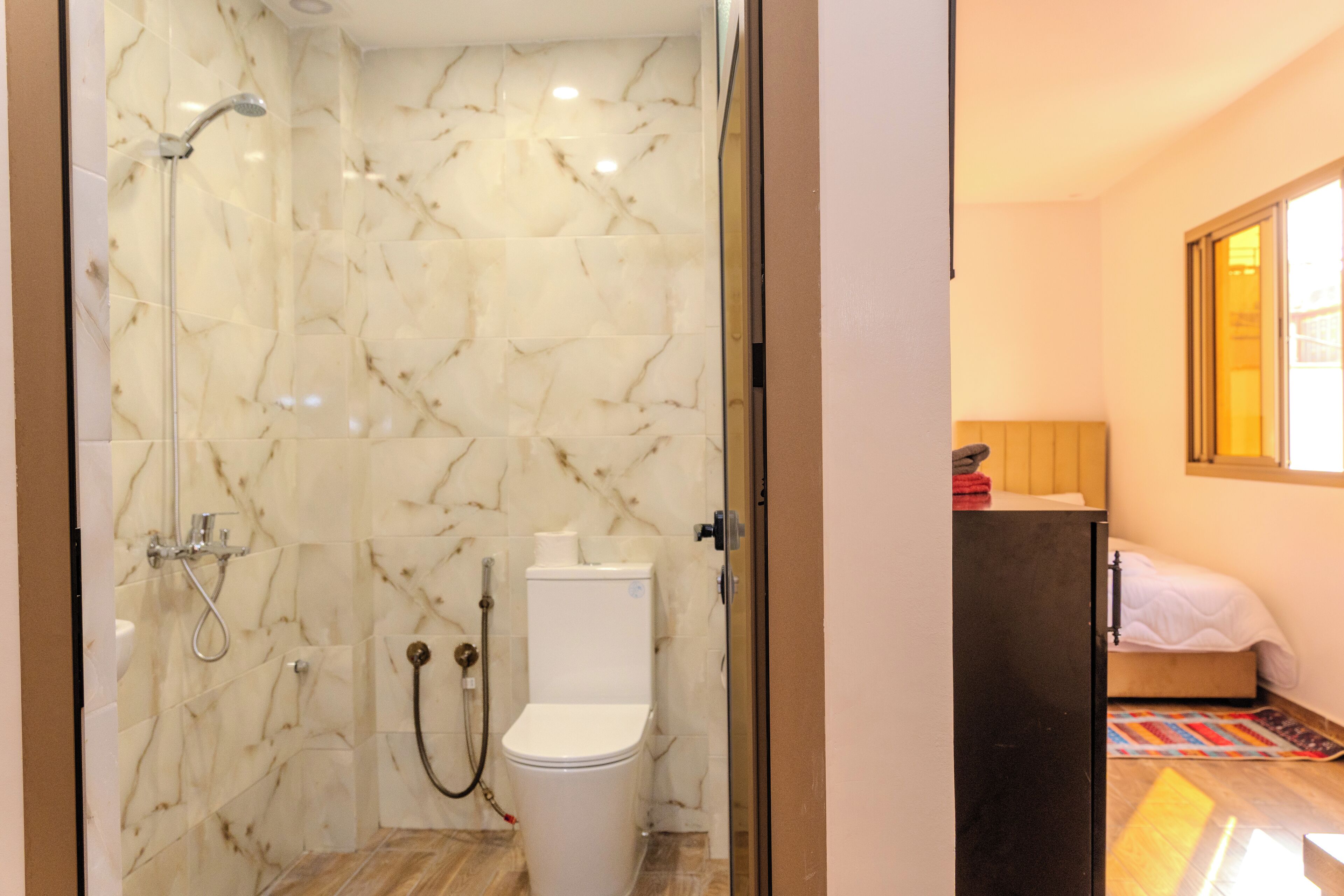 A bathroom with a shower, toilet, and marble walls.