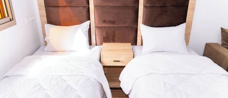 A double bed with a wooden headboard, a bedside table, and a nightstand.
