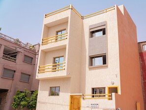 Un immeuble à plusieurs étages, doté de balcons, d’une porte jaune et d’un escalier apparent.