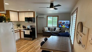 Una cocina compacta con zona de comedor, piso de madera y ventilador de techo.