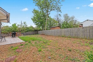 Ein Garten mit Holzzaun, Grill und Terrassenbereich.