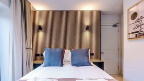 A hotel room with a bed, two bedside tables, a wall-mounted light, and a framed picture on the wall. - Modern 2-Bedroom Apartment with Parking (Conwy Principal Area)