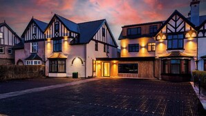 A traditional Tudor-style building with a driveway and a well-lit entrance. - Modern 2-Bedroom Apartment with Parking (Conwy Principal Area)