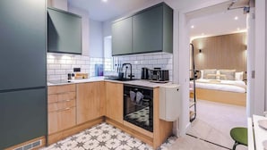 A compact kitchen with a built-in oven and a separate dining area. - Modern 2-Bedroom Apartment with Parking (Conwy Principal Area)