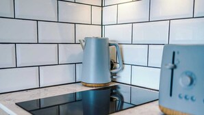 A kitchen with white subway tiles, a blue kettle, and a modern stove.