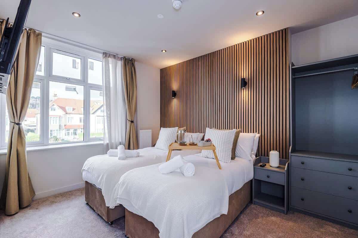 Une chambre d’hôtel avec deux lits, un mur recouvert de lambris en bois, une télévision et une fenêtre avec des rideaux.