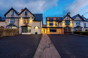 A row of traditional timber-framed houses with a paved driveway and well-lit exterior lighting.