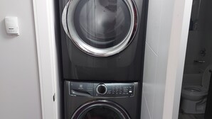 A laundry room with two front-loading washing machines and a toilet visible through an open door.