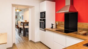 Een moderne keuken met witte kasten, een zwarte magnetron en een rode accentmuur.