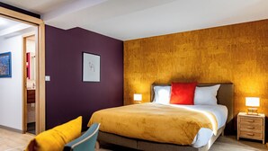 Een moderne slaapkamer met een groot bed, twee nachtkastjes en een fauteuil.