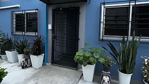 A blue building with a black door, multiple windows, and potted plants in front. - Munchies Bed&Breakfast (Bangkok)
