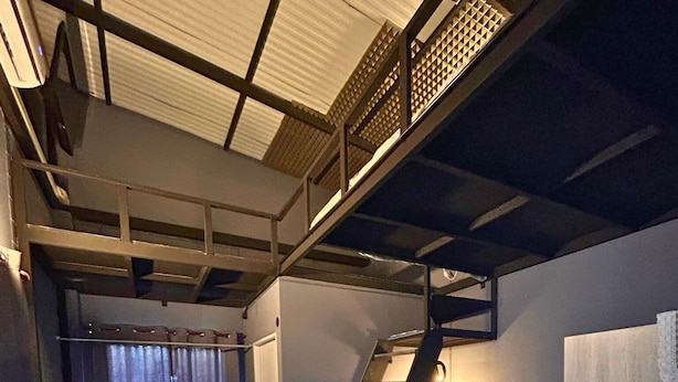 A compact living space with a staircase leading to a loft area, a small kitchenette, and a seating area with a table and chair. - Munchies Bed&Breakfast (Bangkok)
