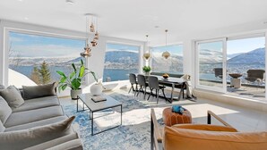 A modern living room with a large window offering a scenic view of mountains and a lake. - Deluxe Villa by Paramount (Troms)