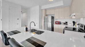 Una cocina moderna con una isla central, electrodomésticos de acero inoxidable y armarios de madera clara.