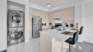 Una cocina moderna con electrodomésticos de acero inoxidable, una isla central y armarios de madera clara.