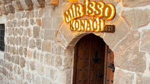 A stone building with a wooden door and a neon sign that reads "Mirissa Konachi 1921". - MİRİSSO KONAK HOTEL MARDİN ARTUKLU (Mardin)
