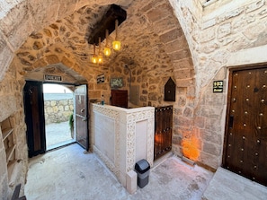 A stone-walled interior with a reception desk, an exit sign, and a door marked '103'. - MİRİSSO KONAK HOTEL MARDİN ARTUKLU (Mardin)