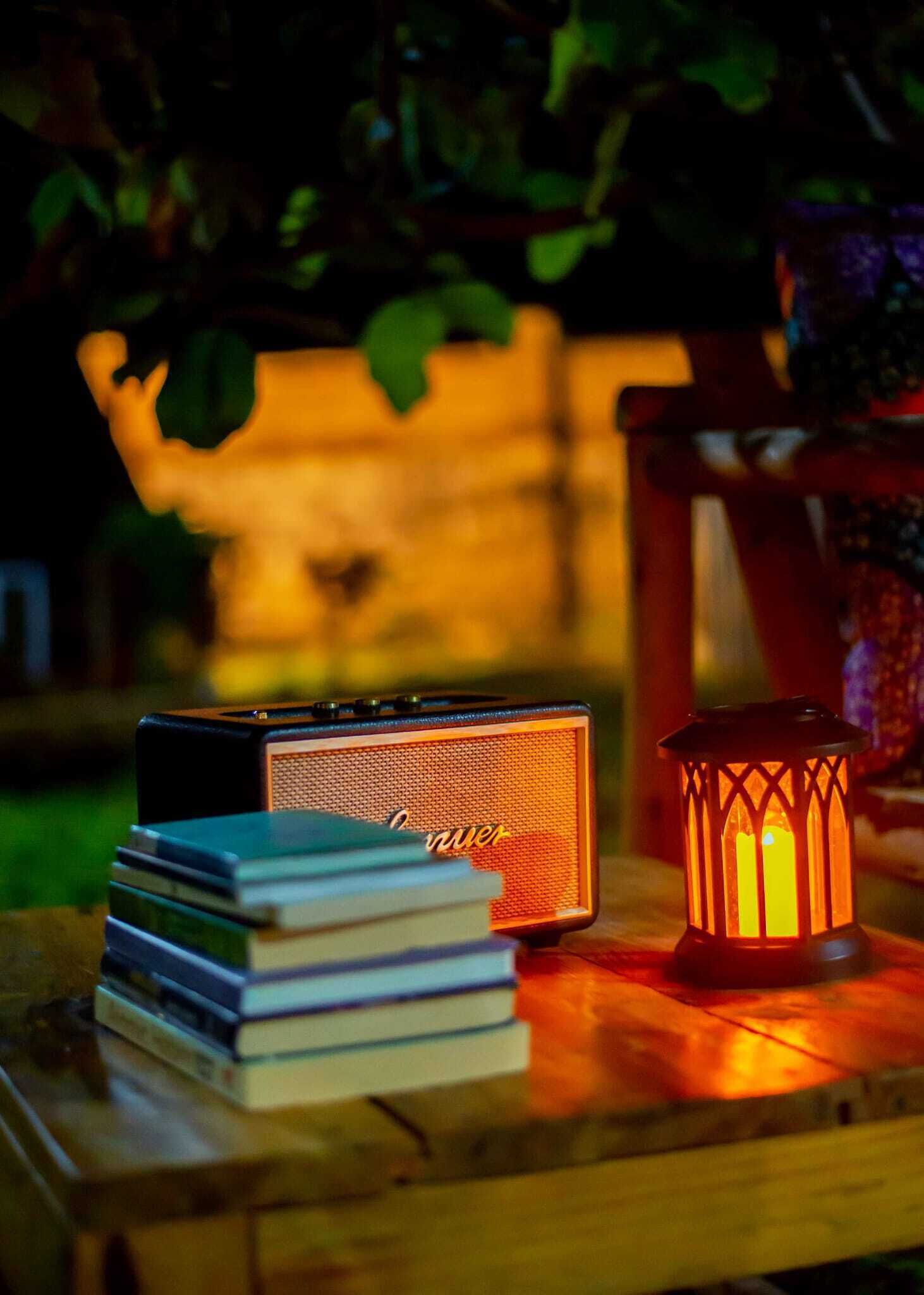 Un altavoz y una vela sobre una superficie de madera.