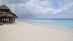 A beach with a wooden structure, a clear sky, and calm waters. - leoglampingznz (Nungwi)