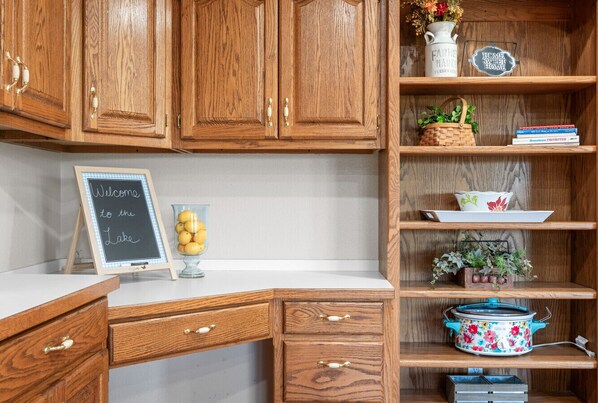 Una cocina con armarios de madera, un letrero de pizarra, un tarro de vidrio con limones y una olla de cocción lenta con estampado floral sobre la encimera.