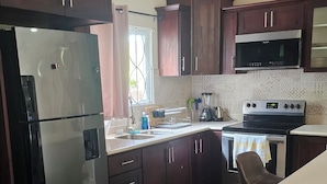Una cocina moderna con armarios de madera oscura, electrodomésticos de acero inoxidable y un taburete de bar.