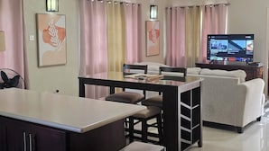 Una sala de estar moderna con comedor, encimera de cocina, cubo de basura y ventilador de techo.