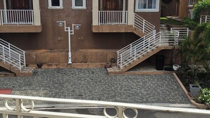 Un edificio de varios pisos con una entrada central, balcones y un patio empedrado.