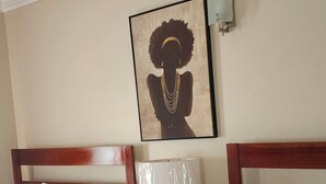 Habitación de hotel con dos camas, ventilador de techo, una obra de arte en la pared y una mesita de noche con lámpara.