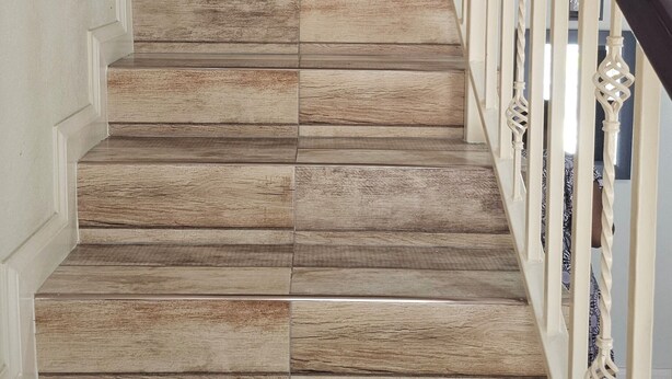Una escalera de madera con barandal blanco y un detalle decorativo en la parte superior.