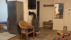 Una sala de estar moderna con un refrigerador grande, un televisor montado en la pared, una chimenea y una zona de estar acogedora.