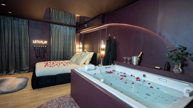 A modern bedroom with a large bed, a jacuzzi, and a neon sign that reads "LET'S PLAY". - Luxury Love Room (Grasse)