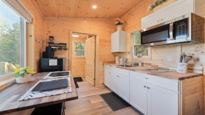 A compact kitchen with wooden cabinets, a microwave, and a coffee machine.