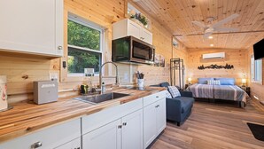 A compact cabin with a kitchenette, a bed, and a bathroom.