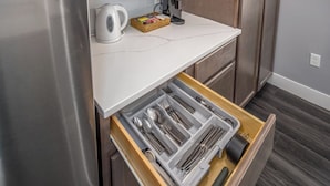 A kitchen with a white countertop, a coffee maker, and a drawer organizer with utensils.