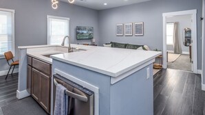 A modern kitchen with a large island, built-in oven, and a dishwasher.