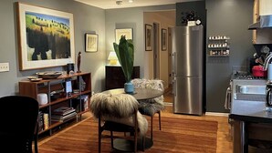 Una sala de estar moderna con comedor, una cocina con refrigerador de acero inoxidable y un cuadro grande en la pared.