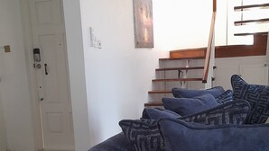 A living room with a dark blue sofa, a staircase, and a door. - Ocho Rios Luxury Ocean View (Ocho Rios)