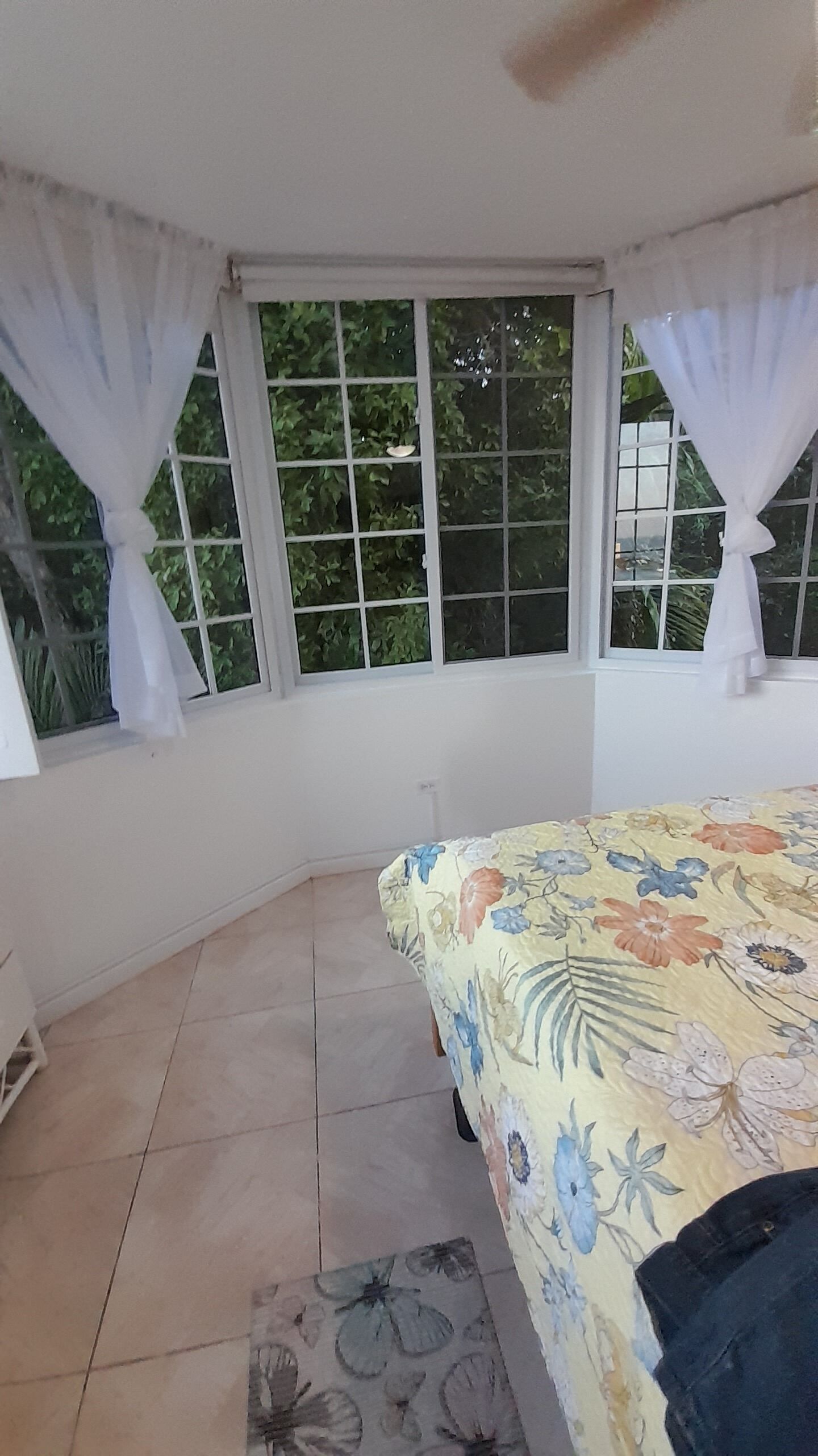 Une chambre à coucher avec un lit, une fenêtre avec des rideaux et une vue sur la verdure à l’extérieur.