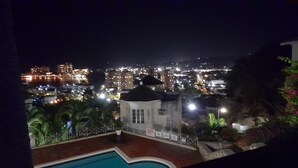 A nighttime view of a cityscape with illuminated buildings and a swimming pool area. - Ocho Rios Luxury Ocean View (Ocho Rios)