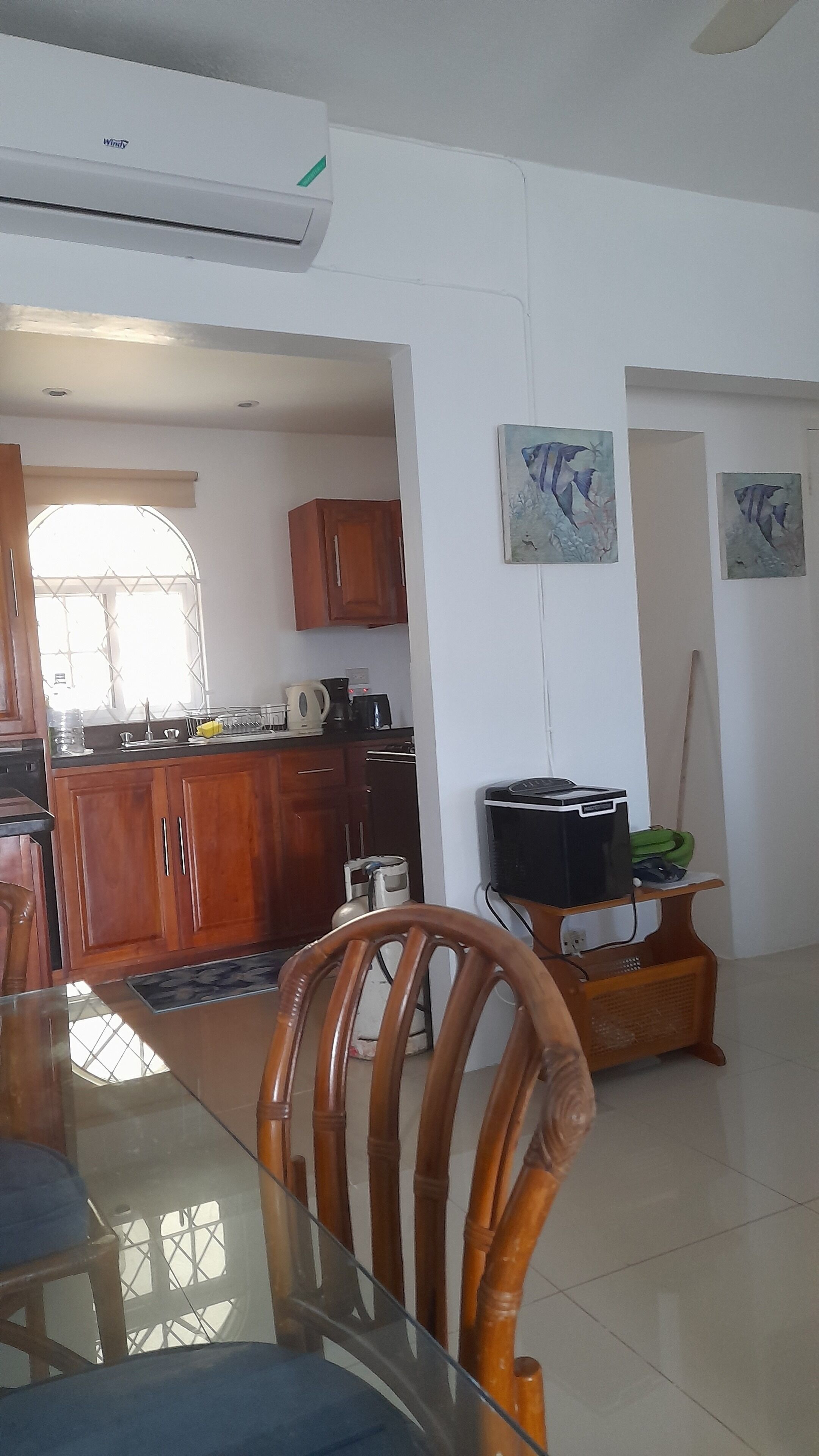 A modern kitchen with wooden cabinets, a dining table with chairs, and a TV stand.