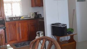 A modern kitchen with wooden cabinets, a dining table with chairs, and a TV stand. - Ocho Rios Luxury Ocean View (Ocho Rios)