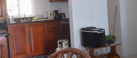 A modern kitchen with wooden cabinets, a dining table with chairs, and a TV stand.
